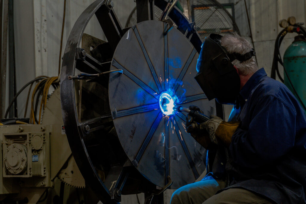 An AirPro employee welds a stainless steel impeller for a pressure blower.