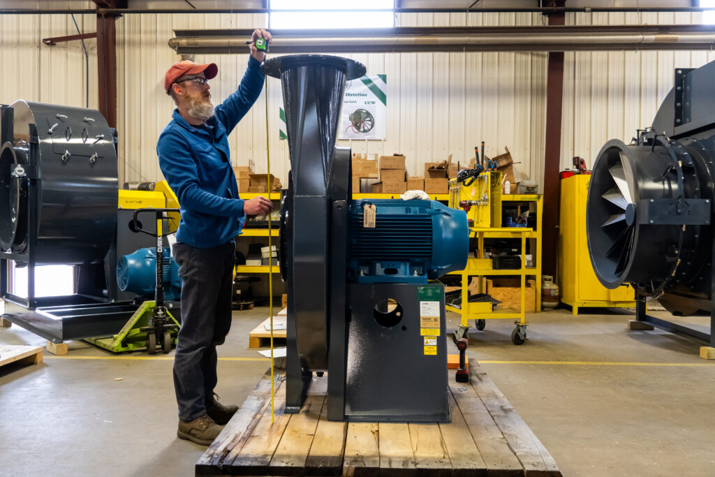 An AirPro employee measures the final pressure blower to prepare it for shipping.